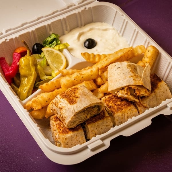 Shawarma wraps, crinkle-cut fries, salad, pickles, and garlic sauce in a white takeout container.